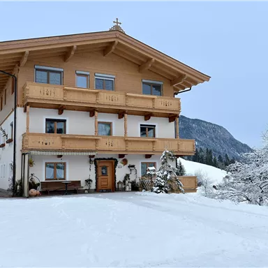 A beautiful house in alpine style, surrounded by snow-covered mountains. The winter gives the scene a calm atmosphere.