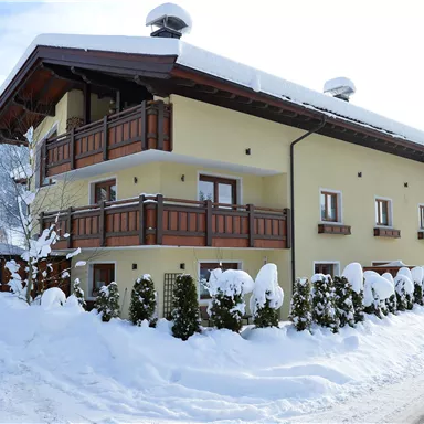 A cozy house in winter, surrounded by snow. The balconies and the landscape create a welcoming atmosphere.