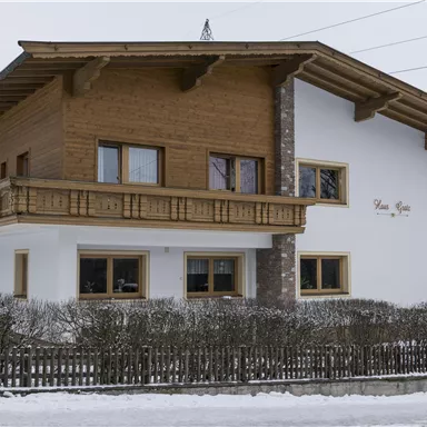 A beautiful, modern house made of wood and stone. Surrounded by snow and mountains, it conveys a cozy atmosphere.