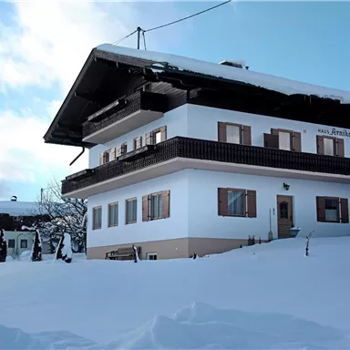 Ein charmantes Haus im Schnee mit einem gemütlichen Winterambiente. Die weiße Fassade und die schneebedeckte Umgebung schaffen eine einladende Atmosphäre.