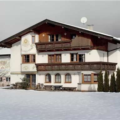 Ein traditionelles alpenländisches Haus im Schnee. Umgeben von einer ruhigen Winterlandschaft.
