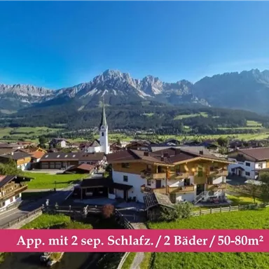 A picturesque alpine landscape with a view of mountains and green meadows. In the foreground, cozy houses and a church can be seen.