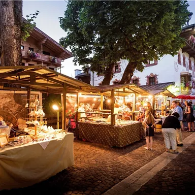 A beautiful night market with colorful stalls and many visitors. The atmosphere is lively and inviting under the evening sky.