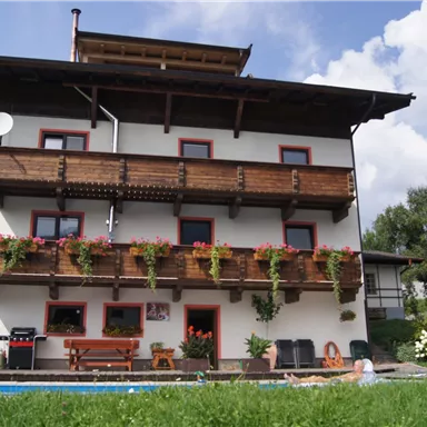 Ein charmantes Haus mit mehreren Balkonen, die mit Blumen geschmückt sind. Der Garten ist grün und einladend, ideal für entspannte Stunden.