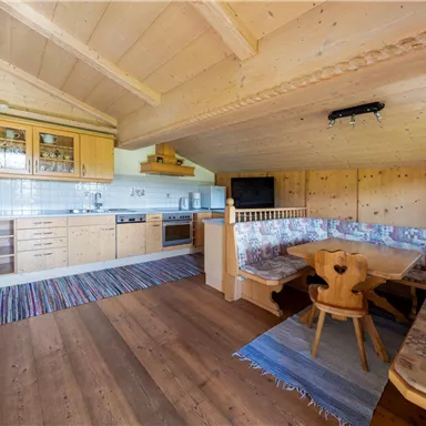Eine gemütliche Küchenzeile aus Holz mit einer Essecke. Der Raum hat Holzdecken und einen warmen, einladenden Charakter.