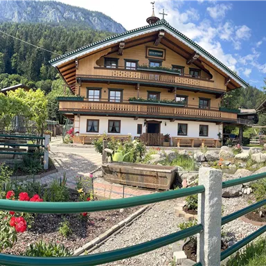 A traditional alpine house with wooden cladding and a blooming garden.