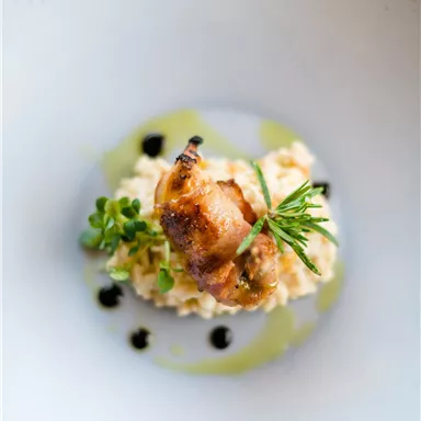 An artfully arranged dish with creamy risotto and a grilled delicacy on top. Fresh herbs and a balsamic reduction give the dish a special touch.