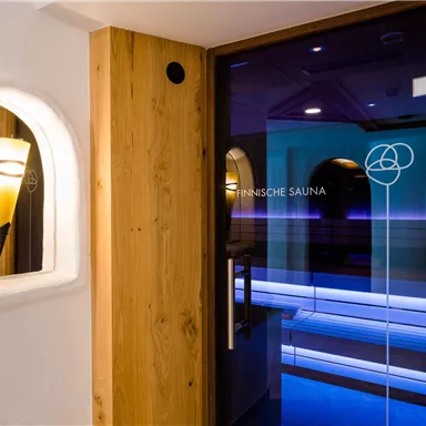 A modern sauna area with a glass door and stylish wooden design. Soft lighting creates a relaxing atmosphere.