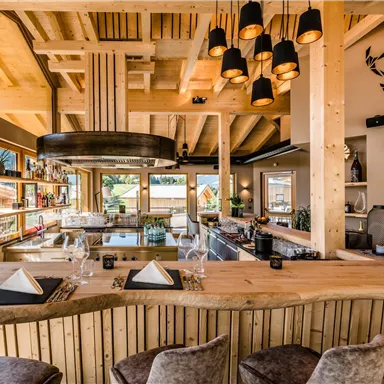 A modern restaurant with wooden interiors and large windows. The bar is stylishly furnished and offers a view of the surroundings.