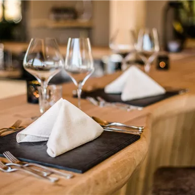 An elegant table set with napkins and glasses in a modern restaurant. The wooden surface and stylish decor create an inviting atmosphere.