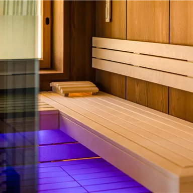 A modern sauna with wooden paneling and soft lighting. The benches provide space to relax and feel good.