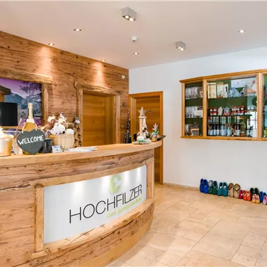 A modern reception area with a wooden counter section. In the background, shelves with drinks and colorful shoes can be seen.