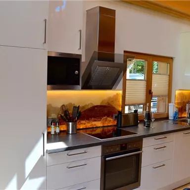 A modern kitchen with elegant wooden paneling. The work area is bright and well-equipped with appliances and ample storage space.