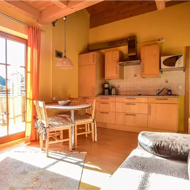 A cozy apartment with a modern kitchen and a dining area. Large windows let in plenty of light and offer a view of nature.