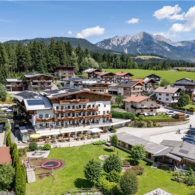 Exterior view of the Hotel Alpenpanorama in Söll with garden, terrace, and view of the Tyrolean mountains.