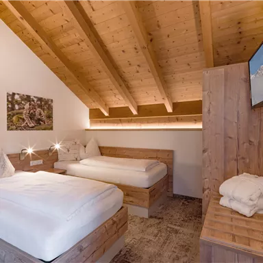 A cozy bedroom with wooden details and two single beds. The decor is modern and inviting, perfect for relaxing overnight stays.