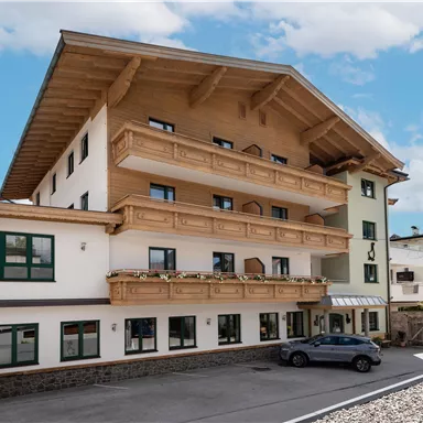 A modern building with several floors and a charming wooden design. It stands in a quiet environment under a blue sky.