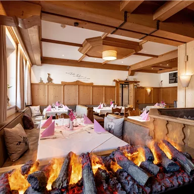 A cozy restaurant with wooden decor and elegant table settings. In the center, a stylish fire burns, creating a warm atmosphere.