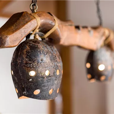 A wooden object with two hanging lamps made of black metal. The lamps have small holes through which the light shines.