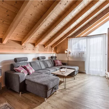 A modern living room with a wooden ceiling and comfortable furniture. A large window area lets in plenty of light and offers a beautiful view.