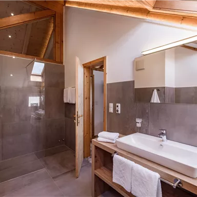 A modern bathroom with a large shower and a stylish vanity. Bright walls and wood details create an inviting atmosphere.