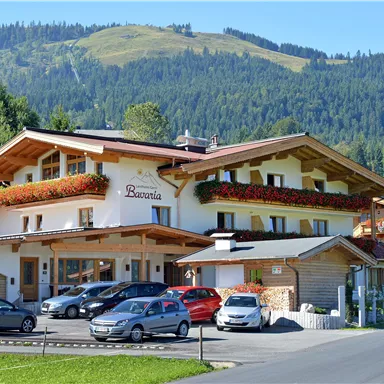 A charming hotel with blooming window boxes in a picturesque setting. Gentle mountains can be seen in the background.