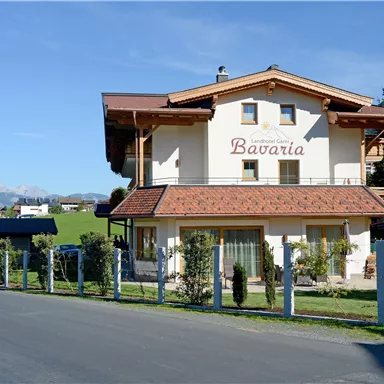 A charming building with the inscription "Bavaria" in a rural setting. In the background, a church and a green landscape can be seen.