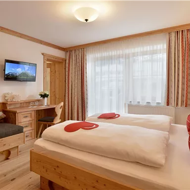A cozy bedroom with two beds and a seating area. Large windows provide plenty of daylight.