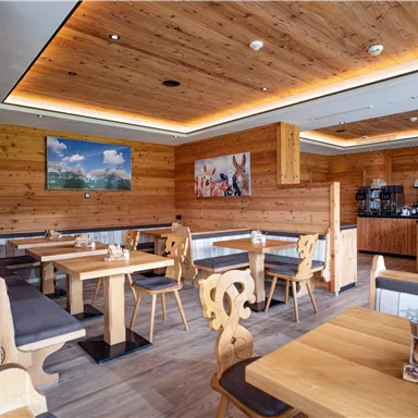Ein gemütliches Restaurant mit Holzverkleidung und modernen Möbeln. Tische sind ordentlich gedeckt und eine Bar ist im Hintergrund sichtbar.