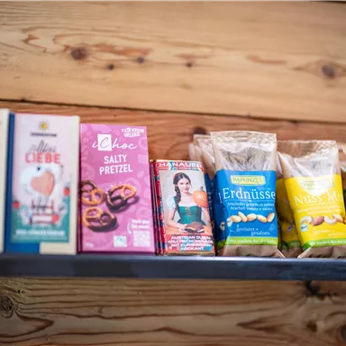 Eine Regale mit verschiedenen Packungen Snacks und Süßigkeiten. Die Verpackungen sind bunt und ansprechend gestaltet.