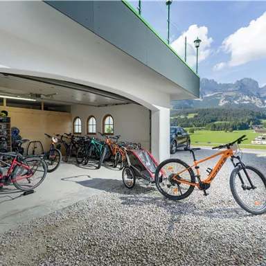 Eine Garage mit mehreren Fahrrädern und einem schönen Bergblick. Die Umgebung ist sonnig und einladend.