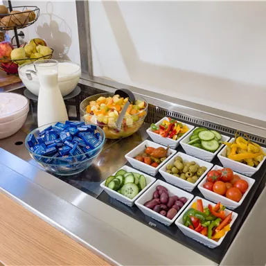 A lavish breakfast buffet with fresh fruit, colorful vegetables, and various sauces. Milk and yogurt round off the offering.