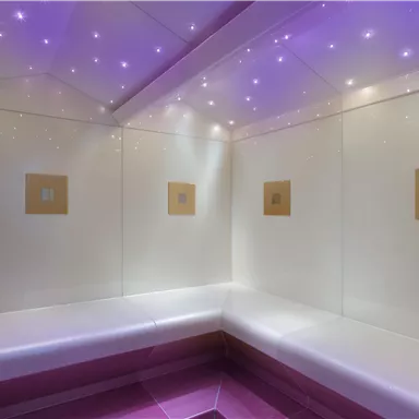 A modern steam bath with white walls and soft lighting. The ceiling is decorated with small, sparkling lights.