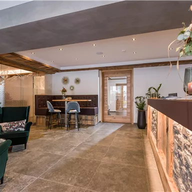 An elegant reception area with modern furniture and warm wooden accents. The atmosphere is inviting and friendly.