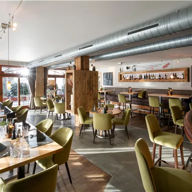 A modern restaurant with stylish furniture and bright lighting. The tables are elegantly set, and the overall atmosphere feels inviting.
