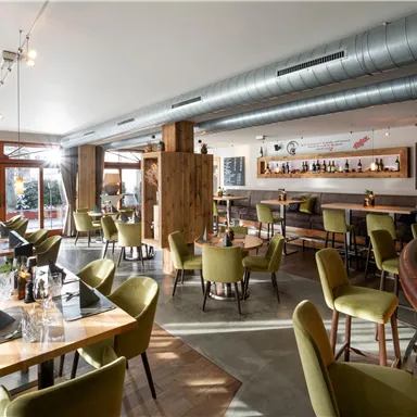 Ein modernes Restaurant mit stilvollen Möbeln und hellem Licht. Die Tische sind elegant gedeckt und die gesamte Atmosphäre wirkt einladend.