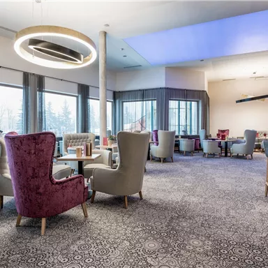 A modern café with cozy armchairs and large windows. The décor is stylish and inviting.