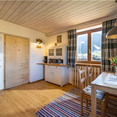 A cozy kitchen with a wooden floor and a large window. The room is brightly lit and invites you to linger.