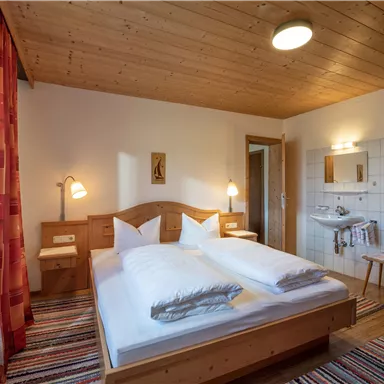 A cozy bedroom with a double bed and wooden decor. Light and friendly colors create an inviting atmosphere.