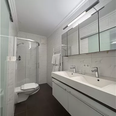 A modern bathroom with a shower and a sink. It has bright walls and an elegant, minimalist style.