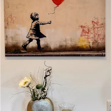A girl holding a red heart balloon stands in front of a gray wall with graffiti. The atmosphere feels nostalgic and emotional.