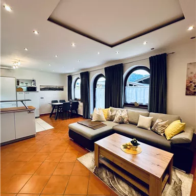 A modern living room with a comfortable sofa and a wooden coffee table. Large windows and stylish decor create an inviting atmosphere.