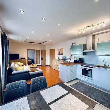 A modern apartment with an open kitchen and cozy living room. Bright colors and stylish furniture create an inviting atmosphere.