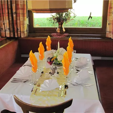 A beautifully set table with orange napkins and glass plates. The decoration and the view give the room an inviting atmosphere.