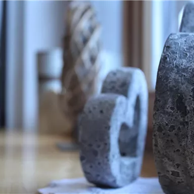 Artful concrete objects are placed on a table. They are arranged in various sizes and shapes.