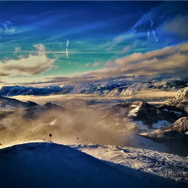 An impressive mountain landscape with snow-capped peaks and clouds. The sky is clear and displays beautiful hues.