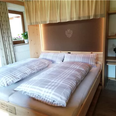 Ein gemütliches Schlafzimmer mit einem großen Doppelbett und karierten Decken. Der Raum ist hell erleuchtet und hat ein warmes, einladendes Ambiente.