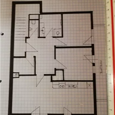 Ein Grundriss eines Hauses mit verschiedenen Räumen. Zu sehen sind ein Wohnzimmer, Küche, Badezimmer und ein Balkon.