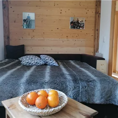 A cozy bedroom with a large bed and a warm blanket. On a table lies a bowl of oranges.