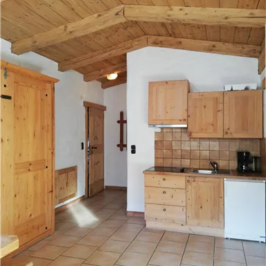A cozy kitchen space with wooden paneling and a practical layout. The bright tiles and wooden details create a warm atmosphere.